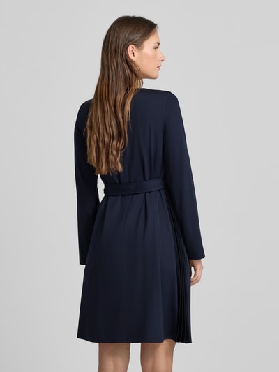 Männermodel trägt Regular Fit Jersey-Kleid mit Lyocell-Anteil Modell 'TALAMO' von Weekend Max Mara, granatowy, gładki, Mini, plisowany detal, prosta faktura, długi rękaw, pasek z tkaniny, widok całej sylwetki z tyłu.