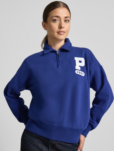 Frauenmodel trägt Loose Fit Sweatshirt aus Baumwoll-Mix von Polo Ralph Lauren in Blau mit weißem Print, glatte Textur, Nahaufnahme Oberkörper. Damen Sweatshirt von Polo Ralph Lauren