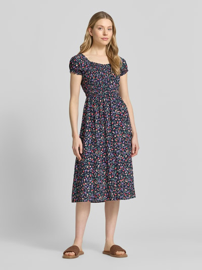 Modelka kobieca nosi Midikleid im Allover-Look od Apricot, kolorowa tkanina w kwiaty, taliowany krój, długość do łydki, widok całej sylwetki z przodu, wykonany z czystych włókien LENZING™ ECOVERO™, dekolt okrągły, długość tyłu w rozmiarze S: 107 cm, szerokość w rozmiarze S: 31 cm.