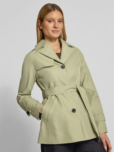 Frauenmodel trägt Regular Fit Trenchcoat aus Baumwoll-Mix von s.Oliver RED LABEL in hellem Grün, Reverskragen, Bindegürtel, Nahaufnahme Oberkörper.