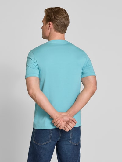 Męski model nosi Regular Fit T-Shirt aus reiner Baumwolle od s.Oliver RED LABEL, gładki jasnoniebieski jersey, krój regular fit, detal z napisem marki, okrągły dekolt, krótkie rękawy, widok całej sylwetki z tyłu.