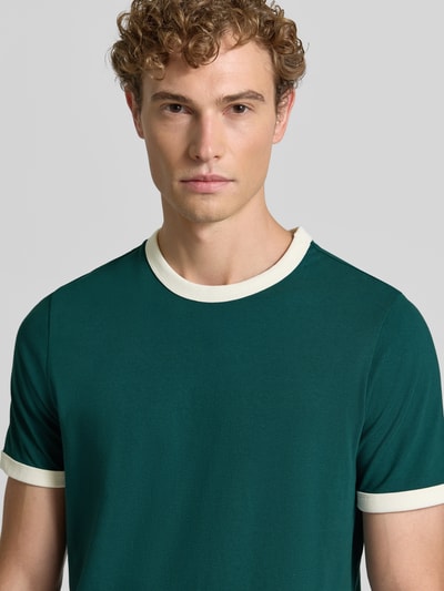 Mężczyzna model nosi Regular Fit T-Shirt aus reiner Baumwolle von MCNEAL, zielony z kontrastowym okrągłym dekoltem i rękawami, bawełna, krój regular fit, Długość tyłu w rozmiarze M: 68 cm, koszulka męska, półzbliżenie na górną część ciała.