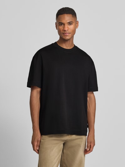 Męski model nosi T-Shirt mit Rundhalsausschnitt Modell 'Carl' von Les Deux z bawełny, prosty krój, detal z logo, długość tyłu 72 cm, Ganzkörperansicht von vorne.
