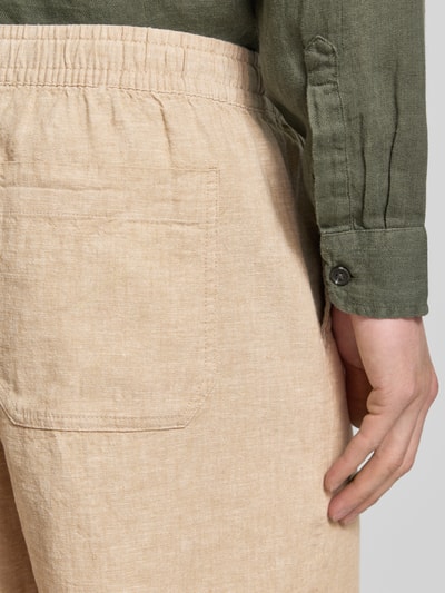 Männermodel trägt Leinenshorts mit elastischem Bund von GAP in Beige, Baumwolle-Leinen-Mix, Loose-Fit, Gesäßtasche, Detailaufnahme. Herren Shorts, Bundweite 42 cm, Innenbeinlänge 17 cm.