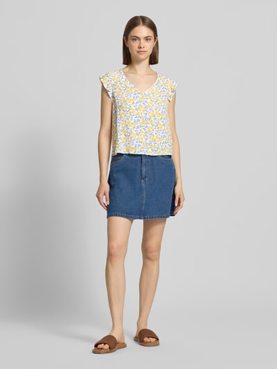 Frauenmodel trägt Regular Fit Blusentop aus reiner Viskose Modell 'BARRI' von Pieces mit abstraktem gelb-weißem Two Tone Muster, V-Ausschnitt, Popeline, Ganzkörperansicht von vorne.