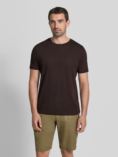 Männermodel trägt T-Shirt mit Rundhalsausschnitt und Label-Stitching von Fynch-Hatton, reine Baumwolle, Regular Fit, in Dunkelbraun, glatte Textur, Ganzkörperansicht von vorne.