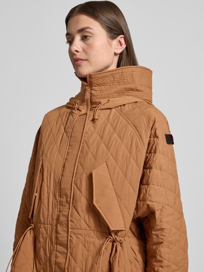 Frauenmodel trägt Relaxed Fit Jacke in Stepp-Optik Modell 'Texel' von Peuterey in Braun mit Stehkragen, Pattentaschen, Tunnelzug, Nahaufnahme Oberkörper. Rückenlänge 80 cm, Schulterbreite 50 cm, Brustweite 72 cm, Ärmellänge 59 cm.