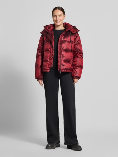 Modelka nosi kurtkę Regular Fit Jacke mit Daunen-Feder-Füllung Modell 'Jilly' von MOS MOSH, czerwony kolor, z efektem pikowania, kaptur z tunelem, Długość tyłu w rozmiarze S: 62 cm, Szerokość ramion w rozmiarze S: 47 cm, Szerokość klatki piersiowej w rozmiarze S: 54 cm, Długość rękawów w rozmiarze S: 65 cm, wypełnienie z puchu i pierza, całkowity widok z przodu.