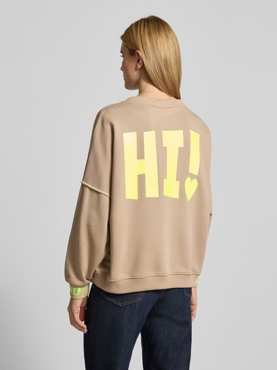 Modelka nosi Oversized Sweatshirt mit Label-Detail von miss goodlife, beżowa bluza z bawełny, prążkowane wykończenia, okrągły dekolt, detal z logo. Ganzkörperansicht Rückansicht.