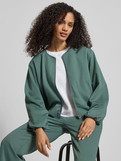 Kobiece modelka nosi Regular Fit Kurtkę z dodatkiem wiskozy model 'Nanni' od FREE/QUENT, elastyczna mieszanka materiałów, okrągły dekolt, zamek błyskawiczny, wpuszczane kieszenie, balonowy fason, kolor zielony, struktura gładka, widok na górną część ciała z przodu.