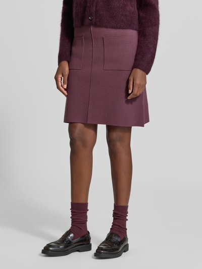 Vrouwenmodel draagt Knielanger rok uit viscosemix van Christian Berg Woman, A-lijn, elastische band, bandwijdte maat S 38 cm, totale lengte maat S 57 cm, bessenrood, zachte textuur, geheelopname van voren