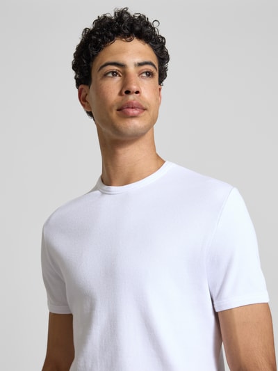 Männermodel trägt T-Shirt in Feinripp mit Rundhalsausschnitt von REVIEW, weiß, Baumwoll-Mix mit Stretch-Anteil, Slim-Fit, Label-Detail, Nahaufnahme Oberkörper.