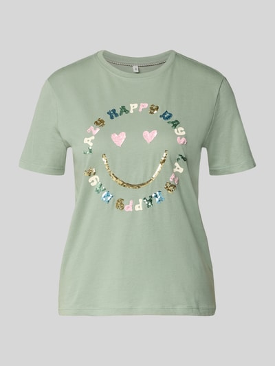 Frauenmodel trägt Damski t-shirt Regular Fit T-Shirt aus reiner Baumwolle Modell 'KITA' von ONLY, efekt: jednolity kolor, krój regular fit, nadruk z motywem, cekinowe obszycie, okrągły dekolt, krótki rękaw, dżersej, bawełna, Ganzkörperansicht von vorne.