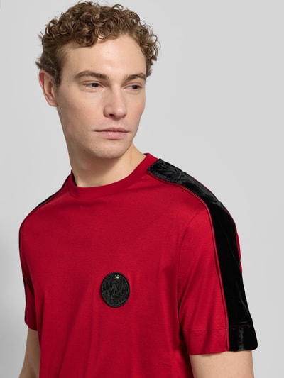 Männermodel trägt T-Shirt mit Label-Detail von Emporio Armani in Rot, Lyocell-Baumwoll-Mix, Regular-Fit, Rundhalsausschnitt, Nahaufnahme Oberkörper.