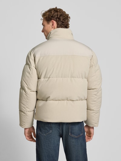 Männermodel trägt Regular Fit Steppjacke mit Label-Patch Modell 'Ocord' von BOSS Orange in Beige mit Cordstruktur, Ganzkörperansicht Rückansicht.