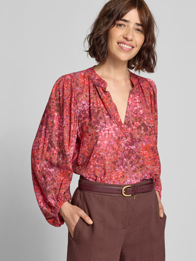 Frauenmodel trägt Relaxed Fit Bluse aus Viskose mit V-Ausschnitt von Rich & Royal in Allover-Look, kräftige Rot- und Rosatöne, Nahaufnahme Oberkörper. Rückenlänge 62 cm, 3/4-Arm, Ärmellänge 53 cm, reine Viskose.