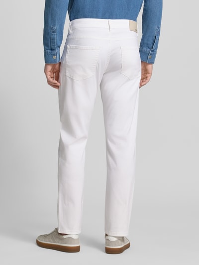 Männermodel trägt Regular Fit Jeans aus Baumwoll-Mix Modell 'MAINE' von BOSS Orange in Optik: Unifarben, Ganzkörperansicht Rückansicht. 5-Pocket-Design und Logo-Applikation, Verschluss: Knopf mit verdecktem Reißverschluss.