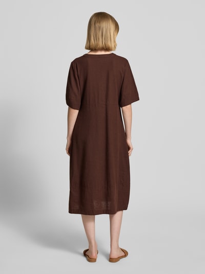 Frauenmodel trägt knielanges Kleid aus Leinen-Viskose-Mix Modell 'Lava' von FREE/QUENT in Braun, A-Linie, Ganzkörperansicht Rückansicht. Leicht strukturierte Textur, V-Ausschnitt, Knopfleiste, Rückenlänge 96 cm, Brustweite 43 cm, Ärmellänge 29 cm.