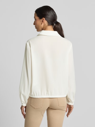Frauenmodel trägt Regular Fit Bluse mit V-Ausschnitt von Marc Cain in Creme mit Hemdblusenkragen und Knopfleiste, Rückansicht Ganzkörperansicht. Rückenlänge 57 cm, Ärmellänge 60 cm.