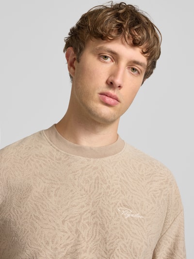 Männermodel trägt Oversized Herren T-Shirt von PEGADOR in Beige aus Baumwoll-Mix, Label-Stitching, Rundhalsausschnitt, Nahaufnahme Oberkörper. Modell 'Murlo'.