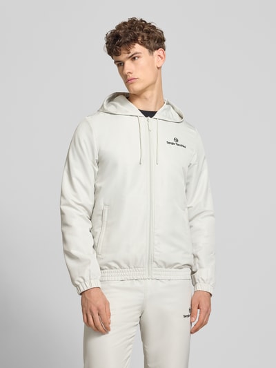 Männermodel trägt Regular Fit Tracksuit mit Logo-Stitching Modell 'Carson' von SERGIO TACCHINI, helle Farben, glatte Textur, Nahaufnahme Oberkörper.