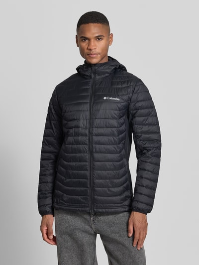 Männermodel trägt Gewatteerd jack met capuchon en logoprint van Columbia, regular fit, ritssluiting, ruglengte maat M 72 cm, schouderbreedte 47 cm, borstwijdte 52 cm, mouwlengte 69 cm, ganzkörperansicht van voren.