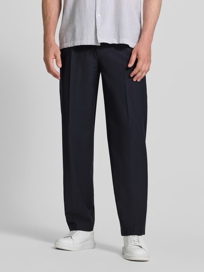 Męski model nosi spodnie Loose Fit Hose mit Bügelfalten Modell 'Lexter' od JOOP!, mieszanka materiałów z dodatkiem wełny, krój loose fit, kanty, szerokość w rozmiarze 50: 46 cm, długość wewnętrzna nogawki 80 cm, kolekcja, granatowe, gładkie, widok całej sylwetki z przodu.