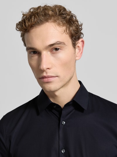 Męski model nosi Super Slim Fit Business-Koszulę z kołnierzykiem typu kent od OLYMP No. Six, mieszanka bawełny i elastanu, czarna, listwa guzikowa, Nahaufnahme Oberkörper.