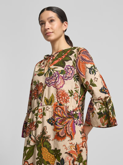 Frauenmodel trägt Midikleid aus Leinen-Baumwoll-Mix im Allover-Look von WHITE LABEL mit bunten floralen Mustern, Nahaufnahme Oberkörper. A-Linie, Schlüsselloch-Ausschnitt, Stufen-Look, Trompetenärmel, Rückenlänge 140 cm, Brustweite 50 cm, Ärmellänge 50 cm.