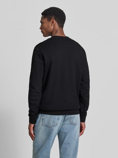 Männermodel trägt Regular Fit Sweatshirt mit Logo-Detail Modell 'Audley' von Guess, schwarzer Baumwoll-Mix, Rückansicht, Ganzkörperansicht Rückansicht. Herren Sweatshirt mit Rundhalsausschnitt und elastischen Abschlüssen, Rückenlänge 69 cm, Ärmellänge 69 cm bei Größe M.