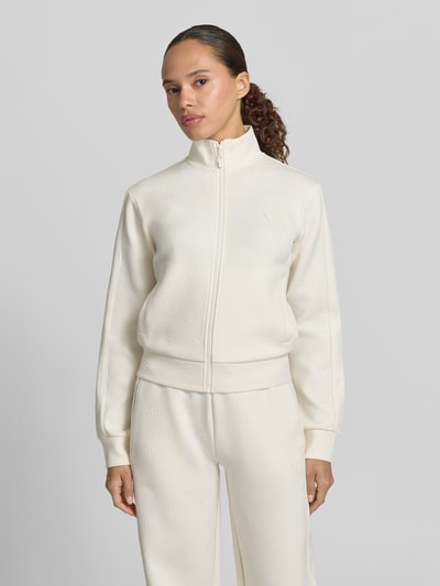 Frauenmodel trägt Sweatjacke mit Logo-Muster Modell 'CALISTA' von Guess Activewear in Creme, Material-Mix, Reißverschluss, Ganzkörperansicht von vorne.