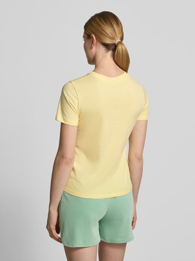 Frauenmodel trägt T-Shirt mit floralem Stitching Modell 'Aminna' von ICHI, Damen T-Shirt aus Reine Baumwolle, taillierte Passform, Rückenlänge 58 cm bei Größe S, Pastellgelb, glatte Textur, Ganzkörperansicht Rückansicht.