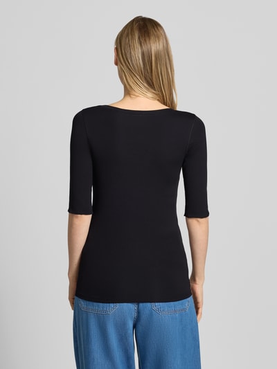 Modelka nosi damski t-shirt 'T-Shirt mit Ärmelaufschlag und Rundhalsausschnitt' od Marc Cain z mieszanki bawełny z dodatkiem streczu, dopasowany krój, okrągły dekolt, rękawy z zakładką, detal z logo, długość tyłu w rozmiarze 36: 60 cm, czarny, gładki materiał, widok całej sylwetki od tyłu.