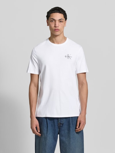 Männermodel trägt weißes T-Shirt mit Rundhalsausschnitt und Logo von Calvin Klein Jeans, reine Baumwolle, Regular Fit, Ganzkörperansicht von vorne.
