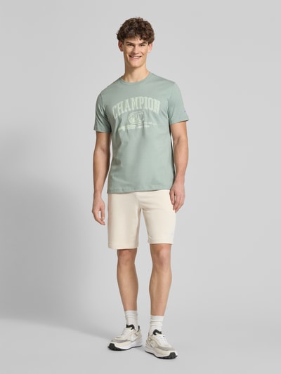 Männermodel trägt Shorts mit Label-Stitching von PUMA PERFORMANCE in Beige, Baumwoll-Mix, Regular Fit, elastischer Bund, Ganzkörperansicht von vorne.