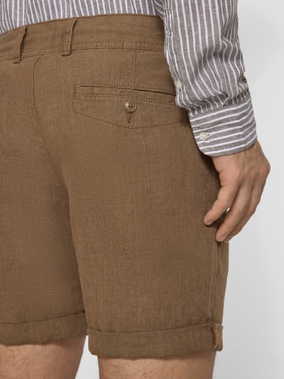 Männermodel trägt Leinenshorts mit Bindegürtel und Gesäßtaschen von MCNEAL in Braun mit Label-Stitching, Reine Leinen, Ganzkörperansicht Rückansicht.