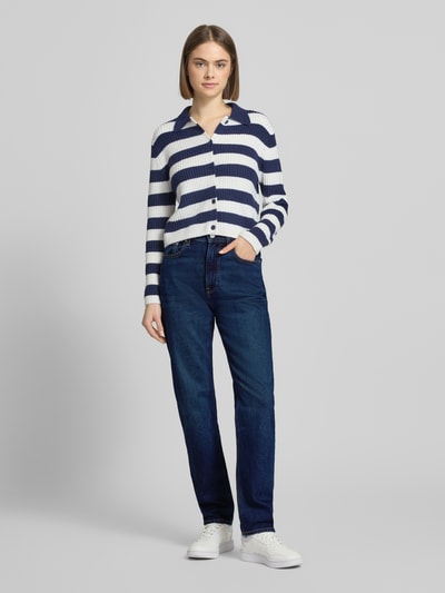 Modelka nosi Straight Fit Jeans mit Logo-Patch Modell 'New Moon' von Calvin Klein Jeans, bawełniany elastyczny materiał, 5 kieszeni, zapięcie na guzik i zamek, szerokość w rozmiarze 27/32: 35 cm, długość nogawki wewnętrznej: 77 cm, granatowy kolor, widok całej sylwetki z przodu.
