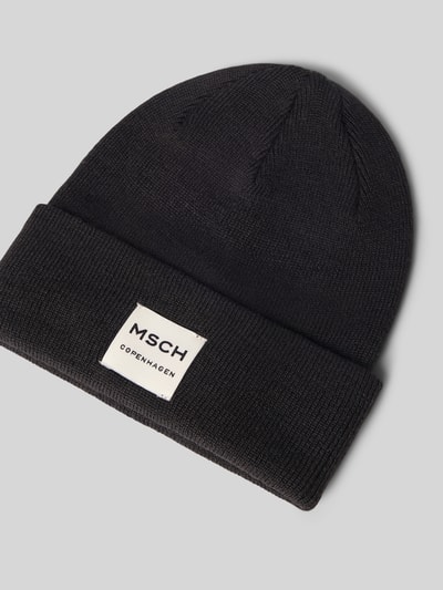 Produktfoto, schwarze Mütze aus Woll-Mix Modell 'Mojo' von MSCH Copenhagen, Strick-Optik, breiter Umschlag, Label-Patch, grauer Hintergrund