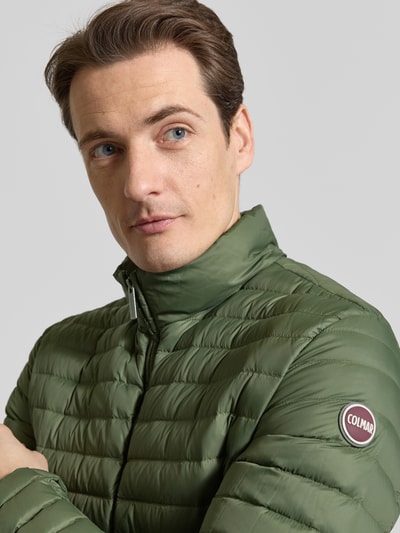 Männermodel trägt Steppjacke mit Zweiwege-Reißverschluss von Colmar Originals in Olivgrün, gesteppte Textur, Nahaufnahme Oberkörper. Regular Fit, Stehkragen, Eingrifftaschen, Rückenlänge 65 cm, Schulterbreite 47 cm, Brustweite 43 cm, Ärmellänge 67 cm.