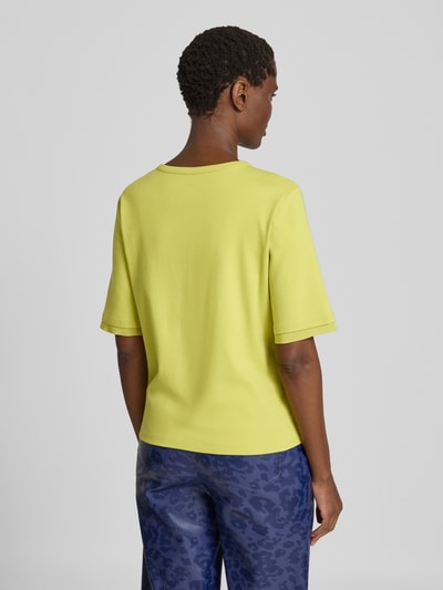 Vrouwenmodel draagt T-shirt met Rundhalsausschnitt und Cut Out van Marc Cain in geel, mix van katoen en elastaan, regular fit, ruglengte maat 36: 55 cm, Ganzkörperansicht Rückansicht.
