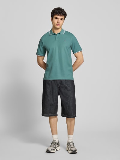 Männermodel trägt Regular Fit Poloshirt mit Strukturmuster Modell 'AUSTIN' von Jack & Jones, Material-Mix, Stitching, Knopfleiste, Ganzkörperansicht von vorne.