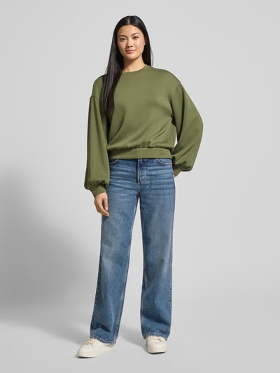Frauenmodel trägt Oversized Sweatshirt mit gerippten Abschlüssen Modell 'Brionna' von MSCH Copenhagen in Olivgrün, Viskose-Mix mit Stretch-Anteil, Rundhalsausschnitt, dezente Struktur, Ganzkörperansicht von vorne.