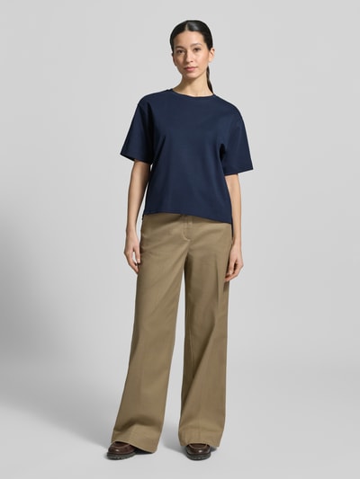 Frauenmodel trägt Regular Fit T-Shirt aus reiner Baumwolle Modell 'MULTID' von Weekend Max Mara in Optik: Unifarben mit Logo-Print, Rundhals-Ausschnitt, Kurzarm, asymmetrischer Rumpfabschluss mit Seitenschlitzen, Materialverarbeitung: Feinripp, Farbe: Dunkelblau, glatte Textur, Ganzkörperansicht von vorne.