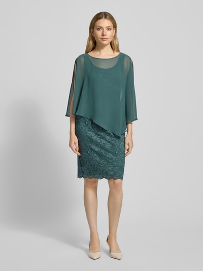 Frauenmodel trägt Knielanges Cocktailkleid im 2-in-1-Look von Vera Mont, Material-Mix mit Stretch-Anteil, Spitze, Gerader-Schnitt, Knielänge, Farbe grün, Rückenlänge 100 cm, Brustweite 44 cm, Ärmellänge 48 cm, Ganzkörperansicht von vorne.
