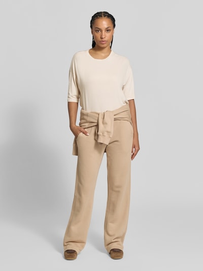 Vrouwenmodel draagt T-shirt met U-Boot-Ausschnitt van Juvia, mix van katoen en modal, relaxed fit, effen beige, halflange mouwen, Ganzkörperansicht von vorne.