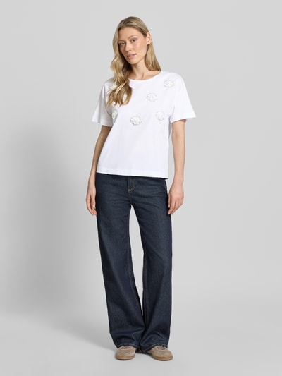 Frauenmodel trägt T-Shirt mit Stitchings und Rundhalsausschnitt von More & More, Damen T-Shirt aus Reine Baumwolle, Regular-Fit, Rückenlänge bei Größe 36 50 cm, Weiß mit dezentem Muster, glatte Textur, Ganzkörperansicht von vorne.