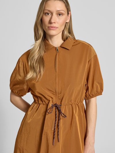 Frauenmodel trägt Midikleid mit kurzem Reißverschluss und Kordelzug an der Taille von Rich & Royal in Braun, Nahaufnahme Oberkörper. Taillierter Schnitt, gerippter Kentkragen, elastische Ärmelabschlüsse, leichte Textur.