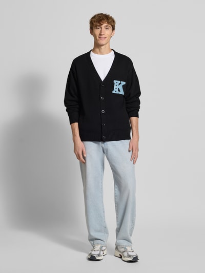 Mannelijk model draagt Strickjacke mit V-Ausschnitt und Stitching van KARL KANI, regular fit, katoenmix, zwarte kleur, voorkant volledig zichtbaar, volledige lichaamsaanzicht.