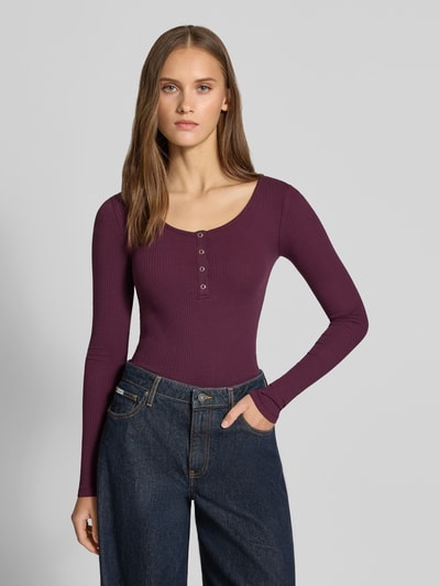Vrouwenmodel draagt Slim Fit shirt met lange mouwen uit katoenmix Model 'KITTE' van PIECES, look: effen, ribstructuur, henley-hals, lange mouwen, kleur bordeaux, textuur fijnrib, katoenmix materiaal, ribverwerking, effen design, niet glanzend, voorkant bovenlichaam close-up.