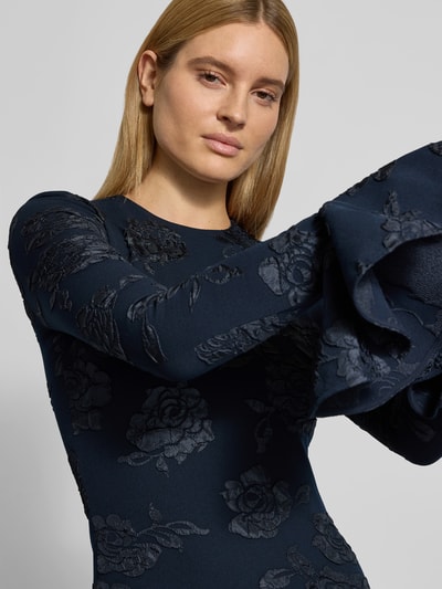Frauenmodel trägt Slim Fit Minikleid mit Rüschenbesatz von ROTATE im Elastischer-Material-Mix, floraler Allover-Besatz, Nahaufnahme Oberkörper.